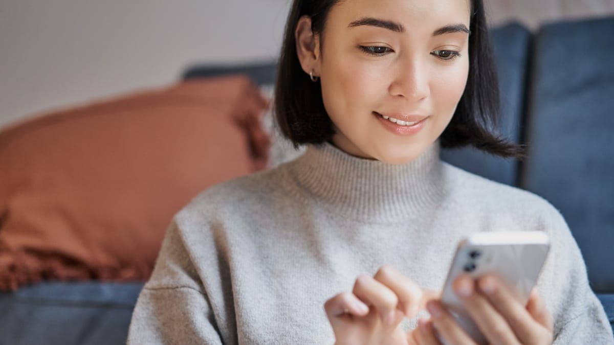 A woman looks happy while using her phone.