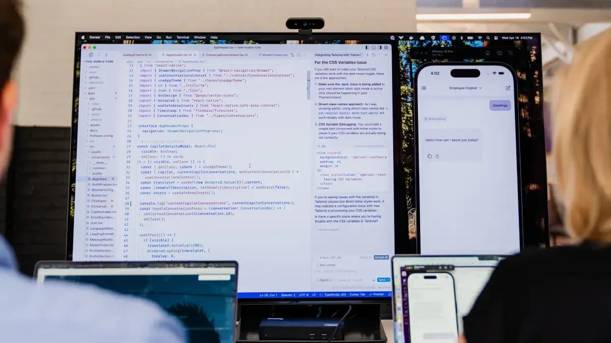 Two people facing a monitor showing lots of code.