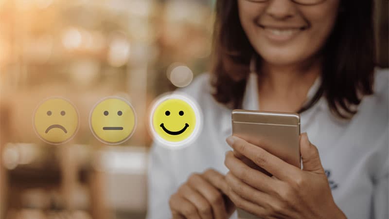 women selecting a happy smiley face on her mobile phone