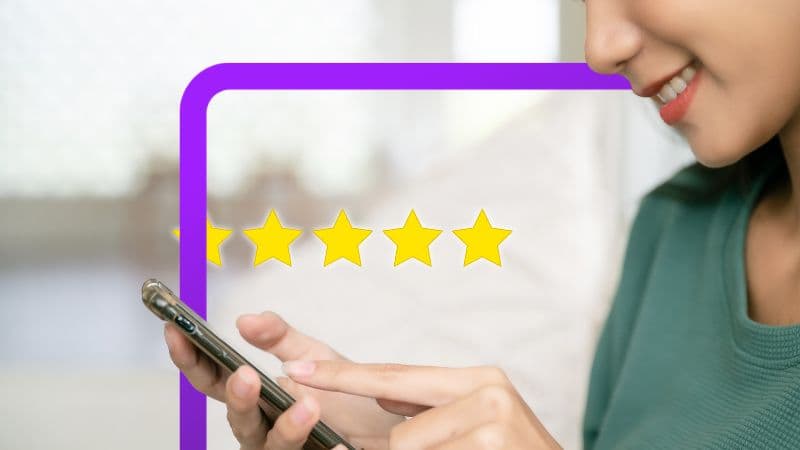 The image shows a smiling woman using a smartphone. Four yellow stars are depicted, seemingly as part of a rating or review displayed on the screen or overlaid on the image.