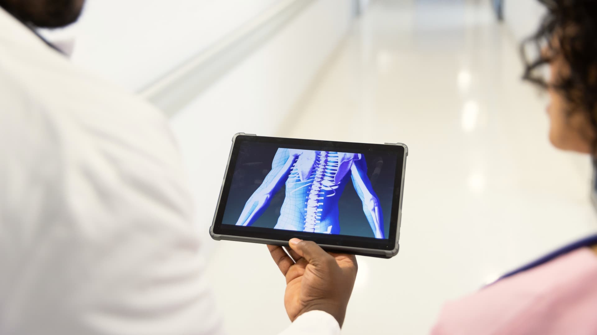 Two people looking at a tablet displaying an Xray image.