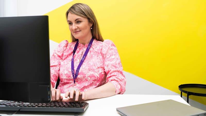 Photograph of a person typing on a laptop with various illustrated elements circling around, including search bars, an envelope, an exclamation mark and a heart