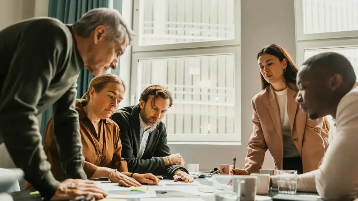 Several people sitting around a boardroom table discussing work matters.