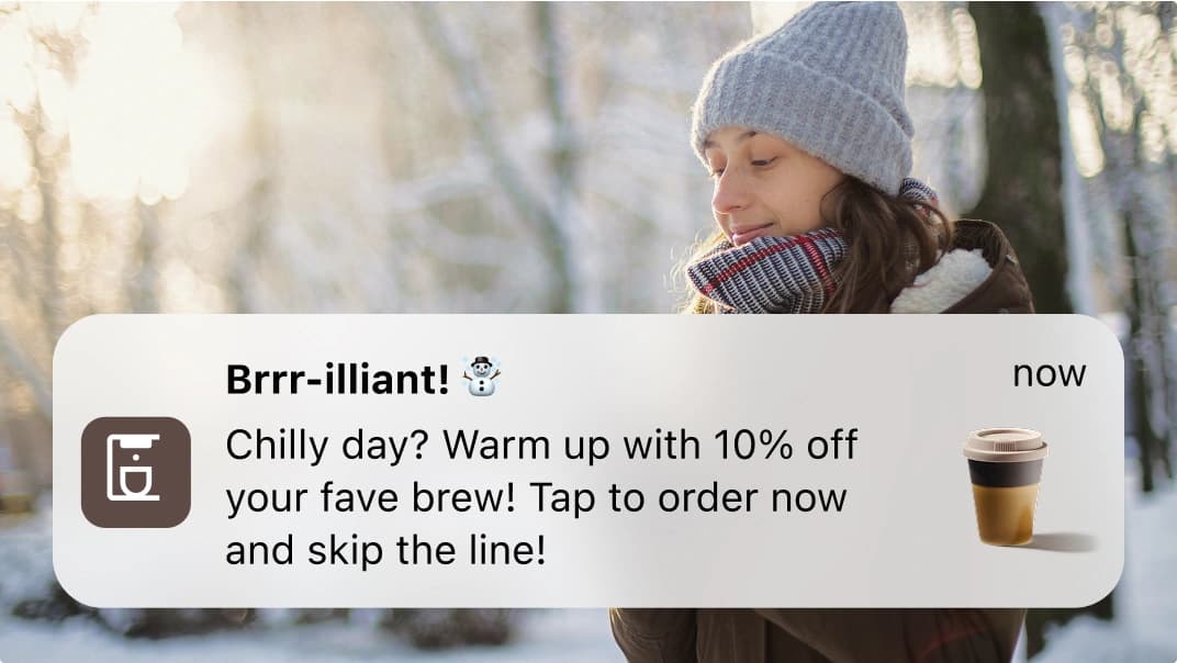 A woman outside dressed for cold weather with a mobile app marketing message to warm up with a discount on coffee.