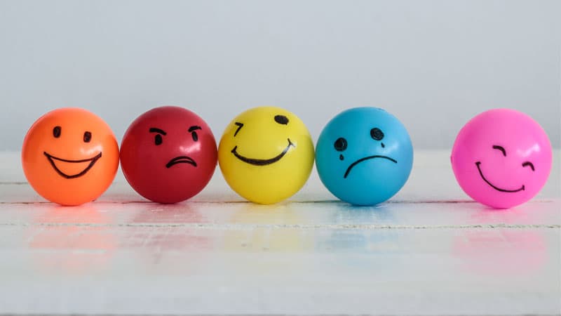 Set of colorful balls with faces drawn on representing different customer emotions.