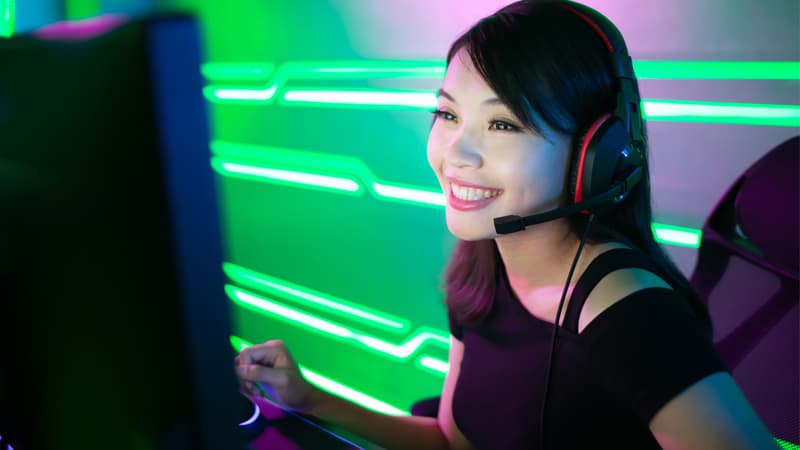 Woman with headset microphone smiling at computer monitor