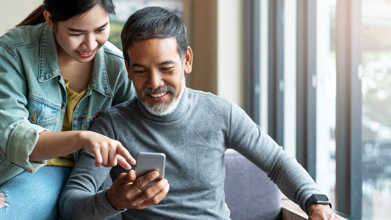Two people looking at a smart phone and smiling