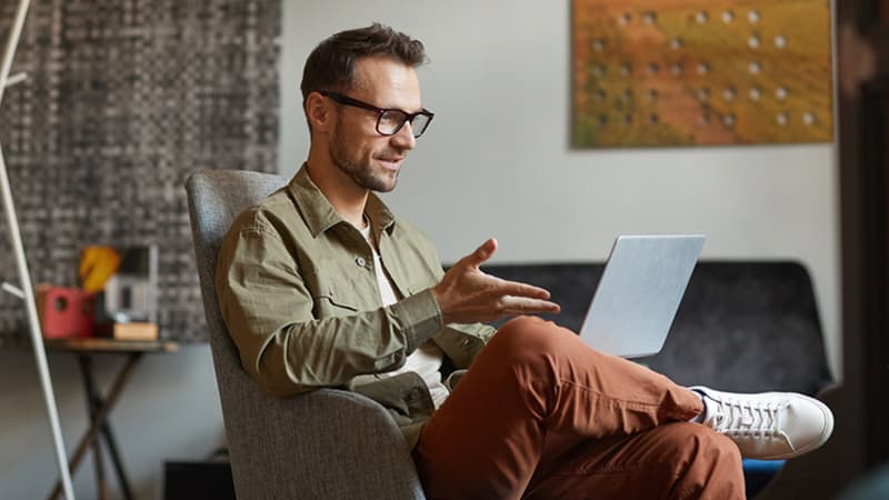 A person holds a meeting, speaking into a laptop