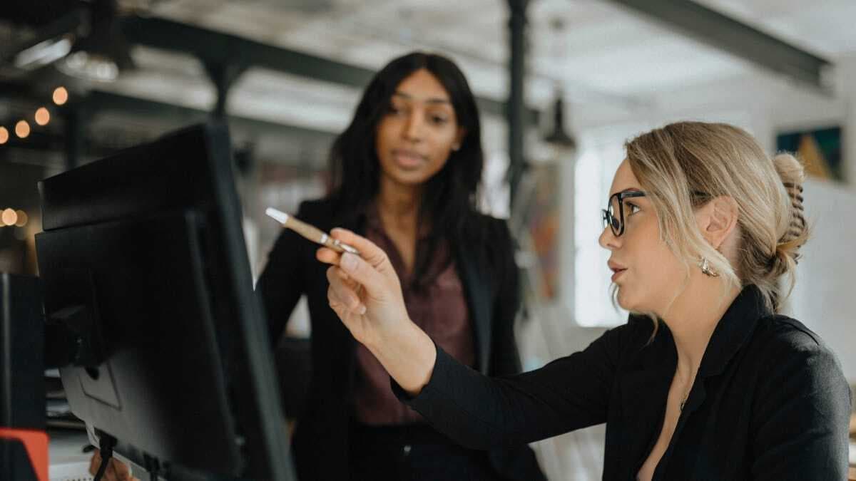 Two women in an office setting collaborate over a project.